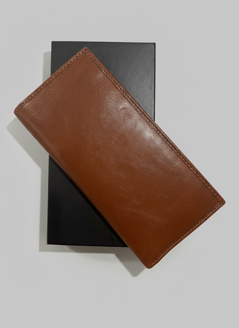 Brown leather wallet on a black book against a light gray background