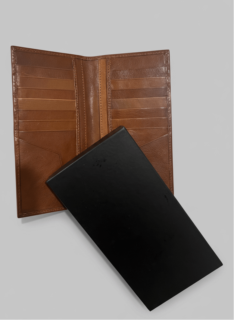 Brown leather wallet and black leather book on a light gray background